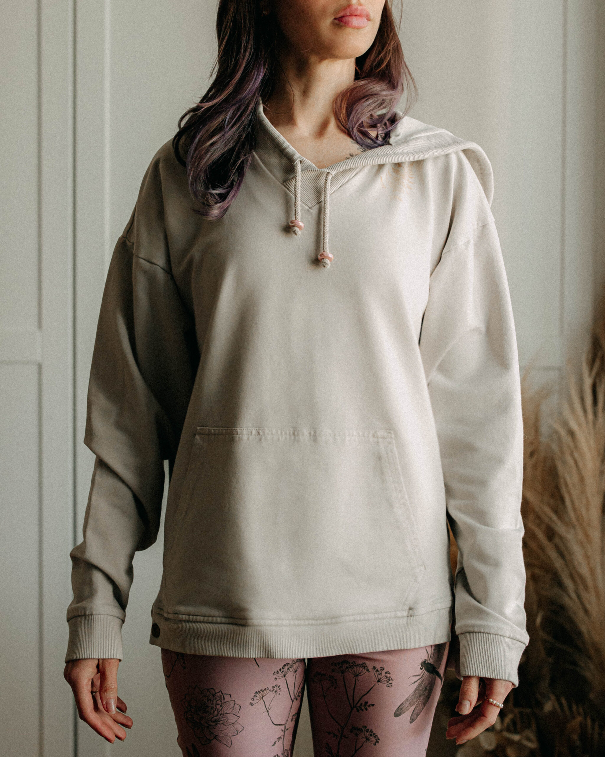 Woman wearing a pale hoodie with the hood up, sleeves long and loose.